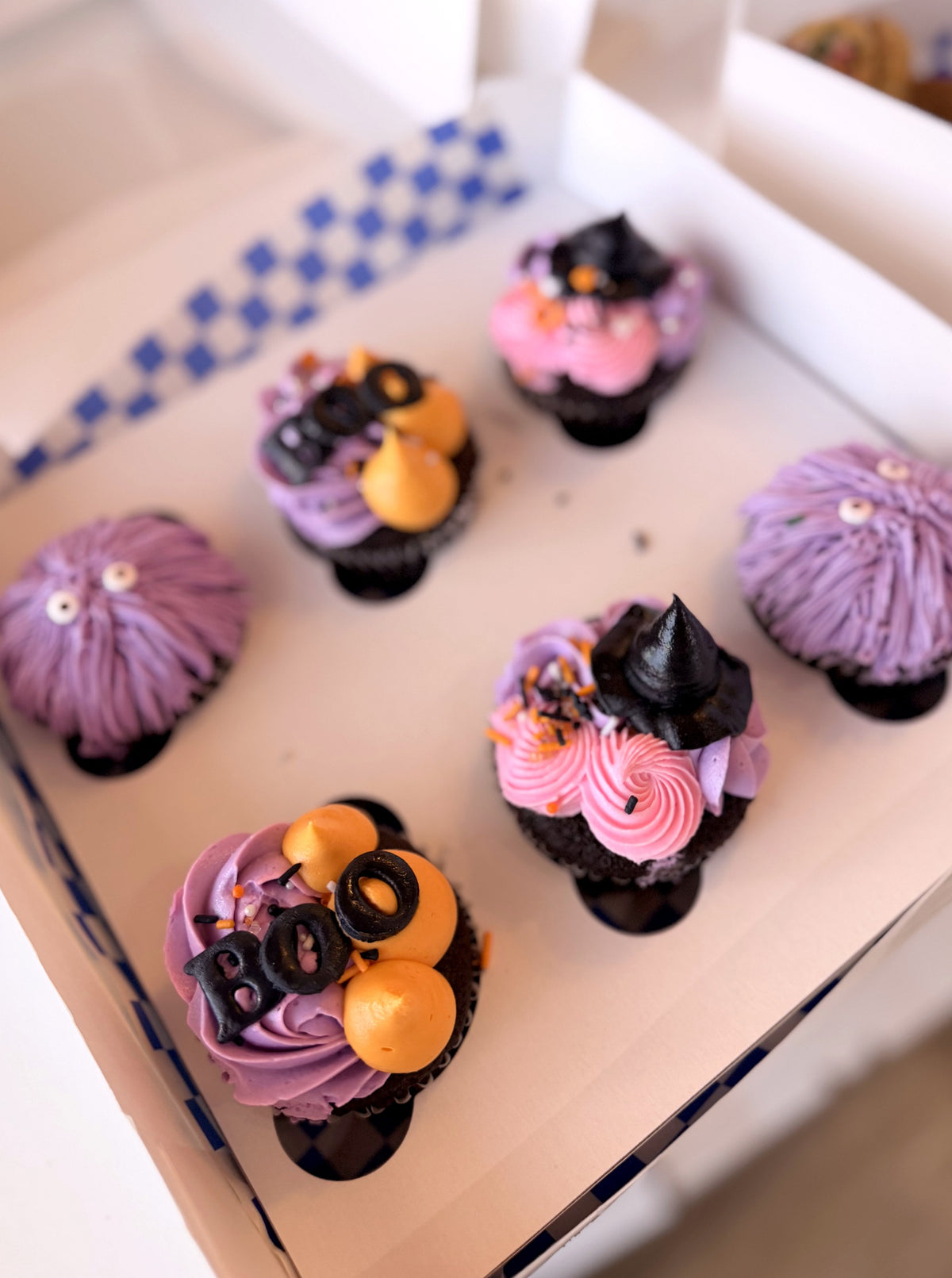 Six decorated Halloween cupcakes in a box